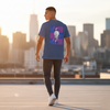 Male model wearing lagoon blue Abstract Notion Tee at sunset, lightbulb back graphic visible, city skyline in background.