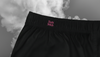 Close-up of Pocket Theory Shorts back waistband — black fabric with concealed neon “Sixth Stitch” embroidery, highlighting fine stitching and subtle design accents.