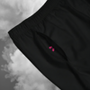 Close-up of Pocket Theory Shorts front pocket — black fabric with neon pink “3 + 3 = 6 hands” embroidery symbol, highlighting fine stitching and subtle design accents.